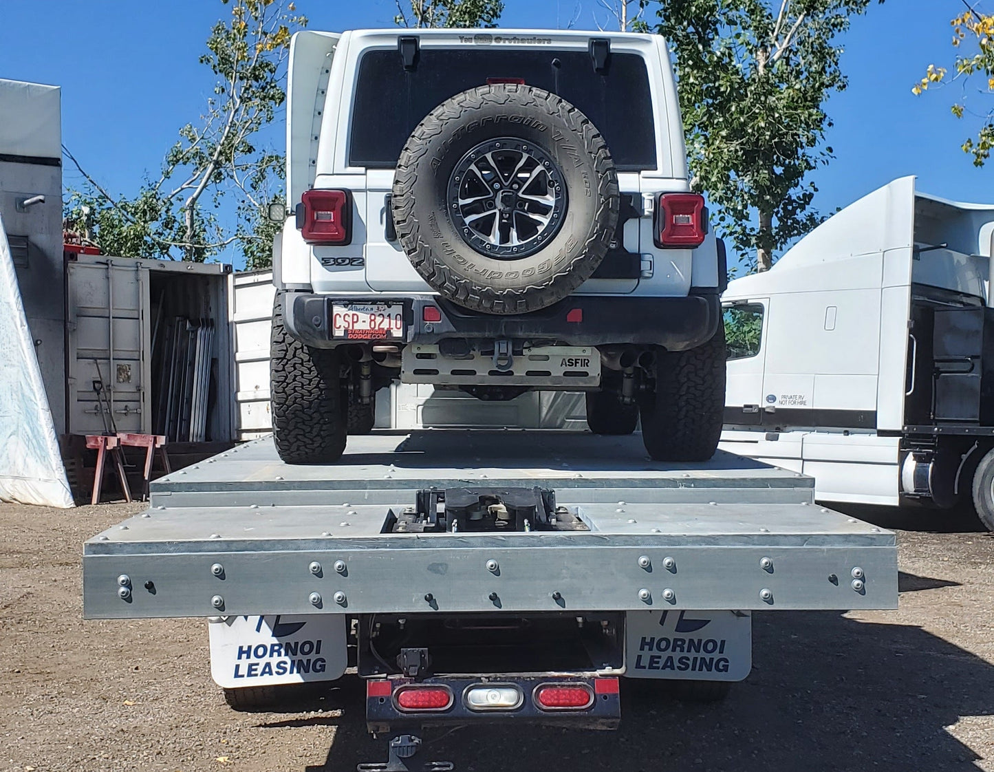 Jeep with spare tire on an RVHauler on a clear day