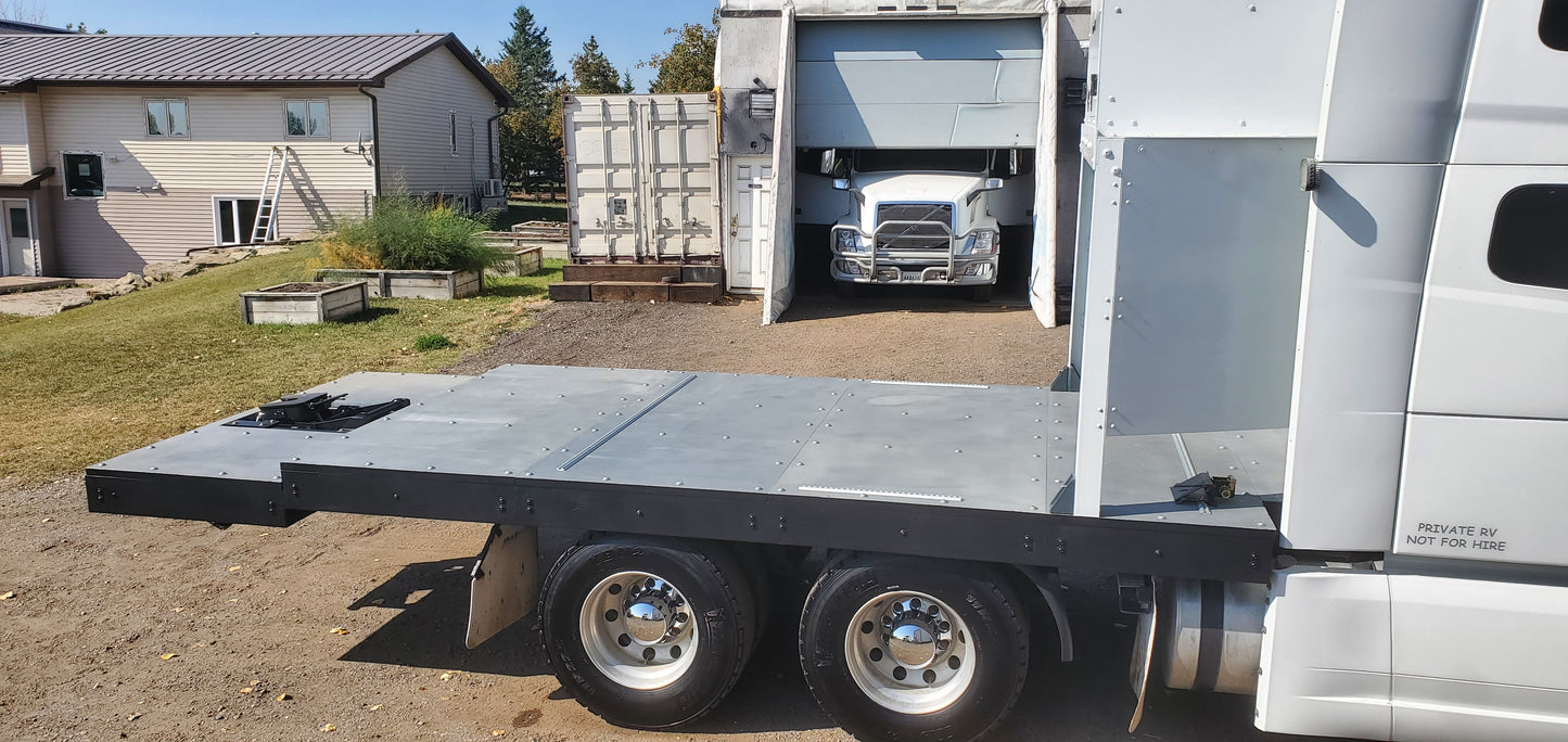 RVHauler truck with a flatbed trailer parked in front of a building.
