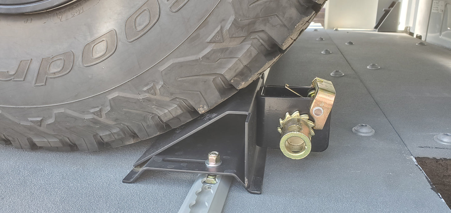 Tire on a car jack with 'GoodYear' branding on a concrete surface.