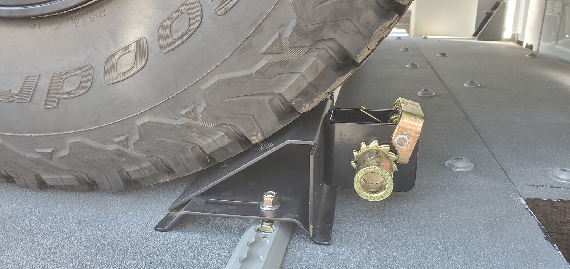 Tire on a car jack with 'GoodYear' branding on a concrete surface.