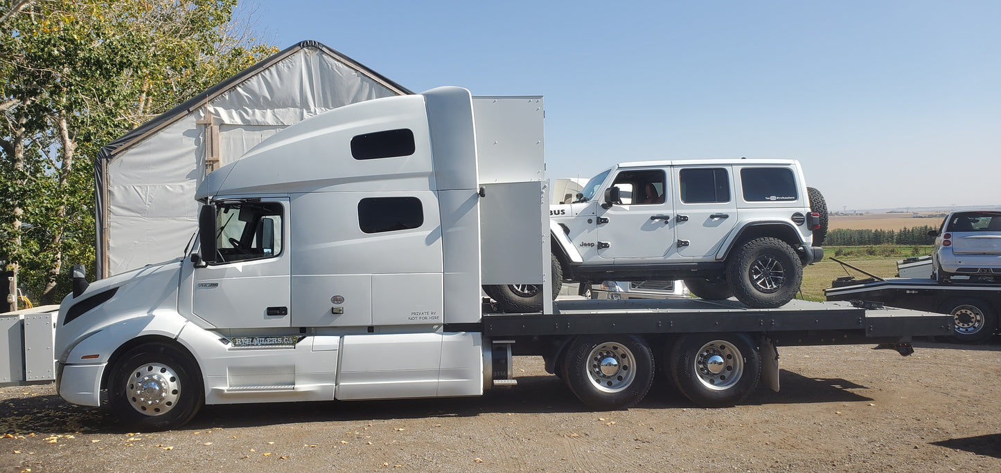 RV Hauler White truck towing a large white camper on a clear day.