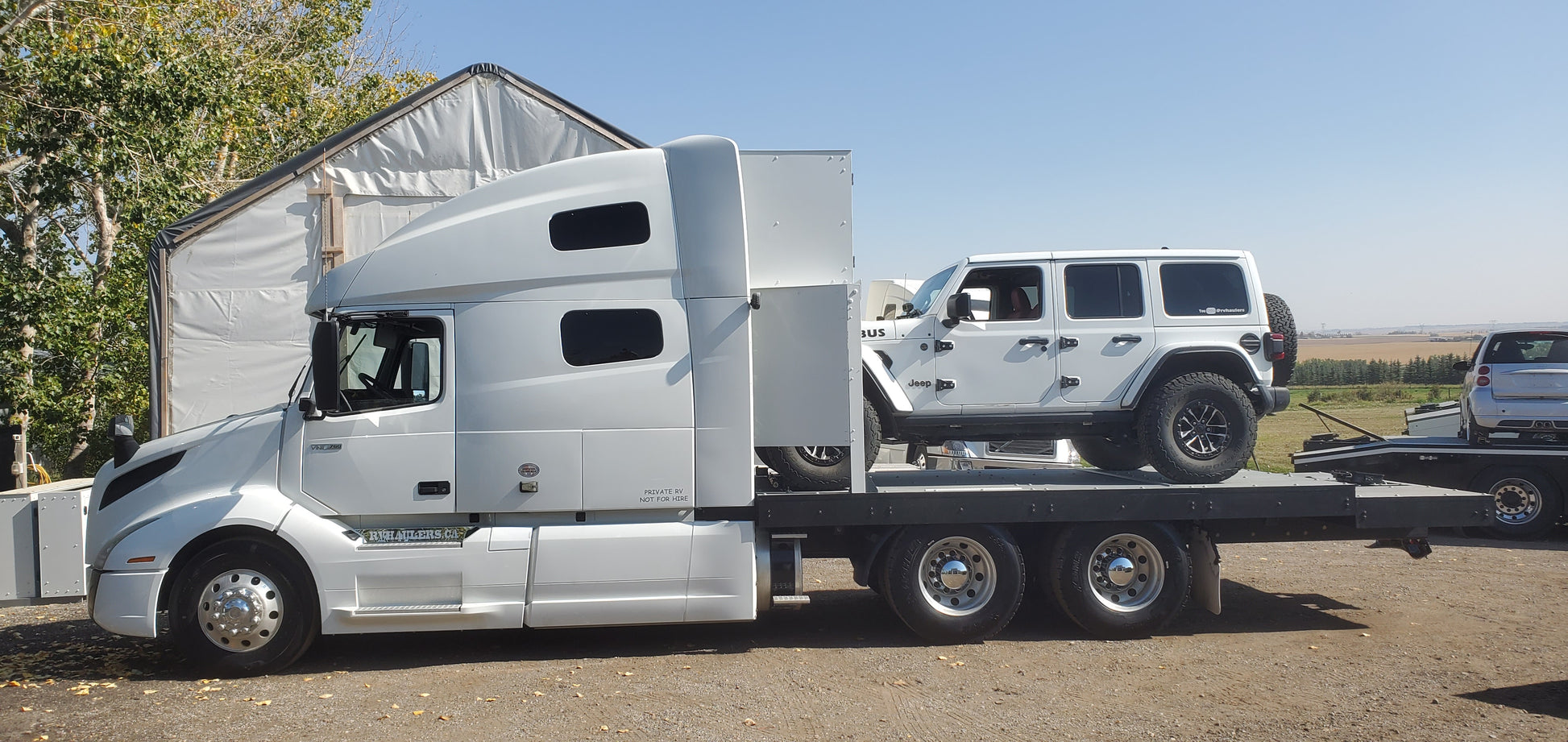 RV Hauler White truck towing a large white camper on a clear day.